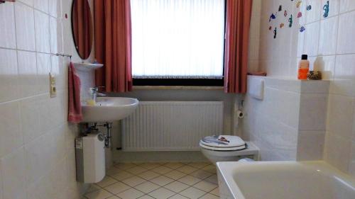 a bathroom with a sink and a toilet and a window at Ferienwohnung an der Almequelle in Alme