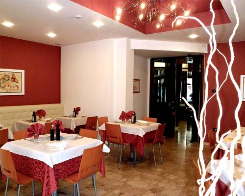 a restaurant with tables and chairs with red walls at Hotel Europeo in Sottomarina