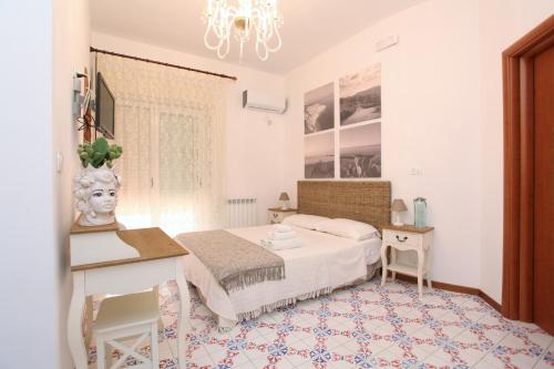 a bedroom with a bed and a desk and a chandelier at B&B Villa Maiolica in San Leone