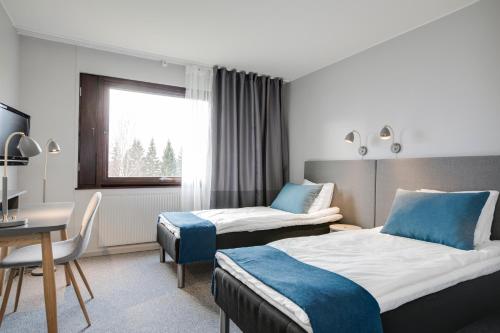 Cette chambre comprend deux lits et un bureau. dans l'établissement Karlskoga Hotell & Konferens, à Karlskoga