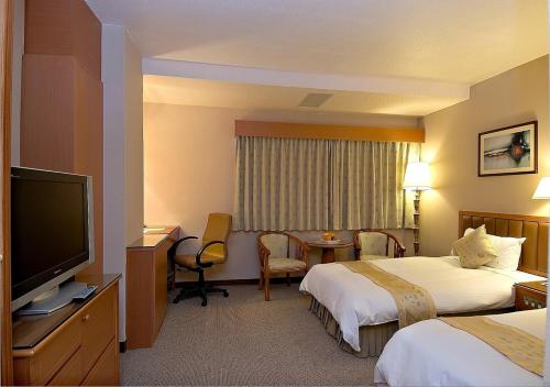 a hotel room with two beds and a flat screen tv at First Hotel in Taipei