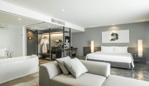 a bedroom with a bed and a bathtub and a couch at ZAZZ Urban Bangkok in Bangkok