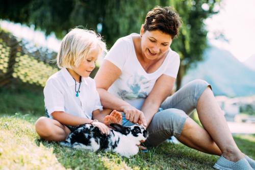 a woman and a child sitting on the grass with a dog at Pitzis Kinderhotel - Family Only in Arzl im Pitztal