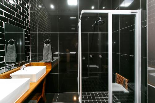 a black tiled bathroom with a shower and a sink at Miles B&B Guest House in Oudtshoorn