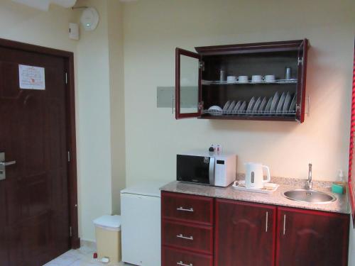 a small kitchen with a sink and a microwave at Al Ferdous Hotel Apartments in Muscat