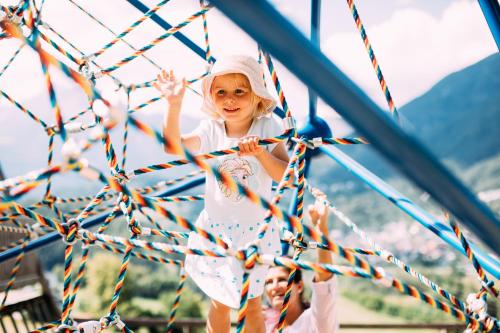 a little girl is climbing on a rope net at Pitzis Kinderhotel - Family Only in Arzl im Pitztal