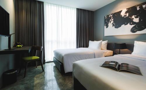 a hotel room with two beds and a desk at ZAZZ Urban Bangkok in Bangkok