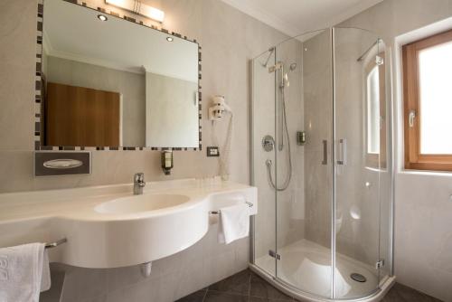 a white bathroom with a sink and a shower at Garni Hotel Bel Vert in Selva di Val Gardena