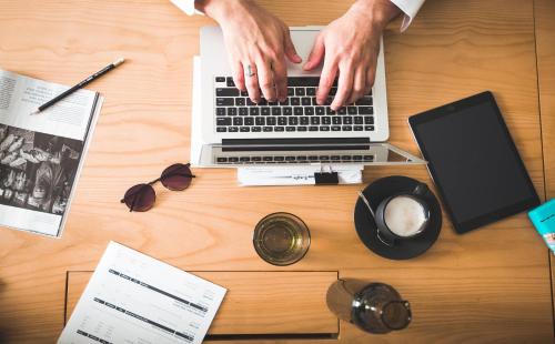 una persona escribiendo en un ordenador portátil en un escritorio de madera en ZAZZ Urban Bangkok, en Bangkok