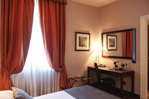 a bedroom with a bed and a desk with a mirror at Allegroitalia San Gallo Firenze in Florence