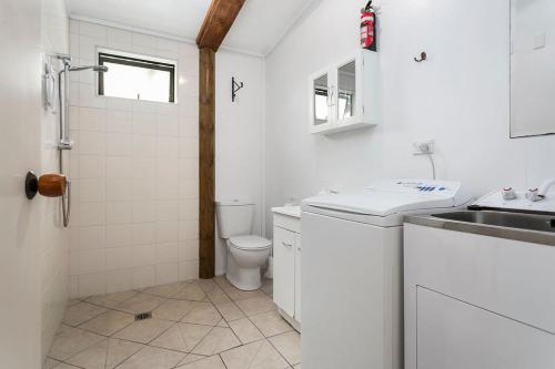 a white bathroom with a sink and a toilet at Pickering Barn Stay in Tamahere
