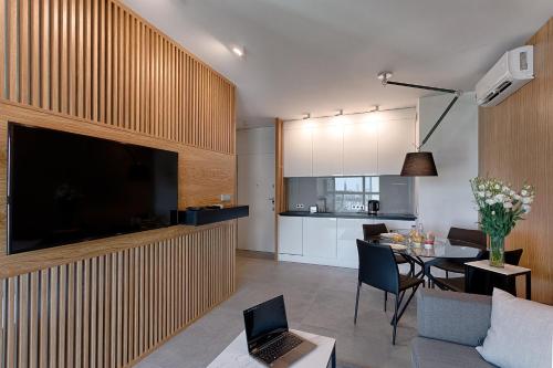 a kitchen and a living room with a table and a television at Mennica Residence in Warsaw