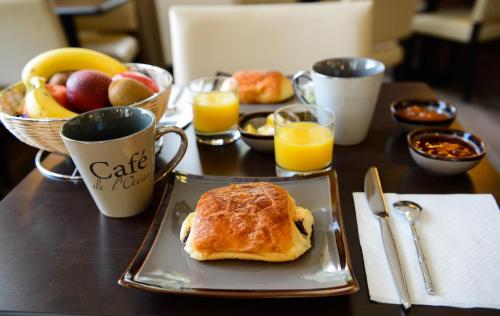 - une table avec une assiette de produits pour le petit-déjeuner et du jus d'orange dans l'établissement Le Taruquet, à Eymet