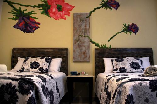 two beds in a bedroom with flowers on the wall at Casa Akbal B&B in Mérida