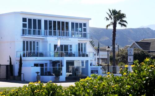 a white building with a palm tree in front of it at Hermanus Boutique Guest House in Hermanus