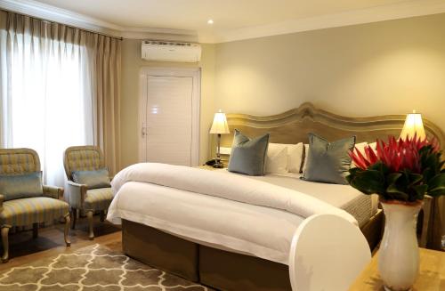 a bedroom with a large bed and a vase of flowers at Hermanus Boutique Guest House in Hermanus