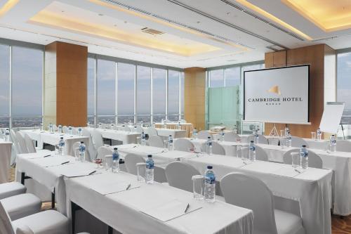a conference room with white tables and chairs and a screen at Cambridge Hotel Medan in Medan