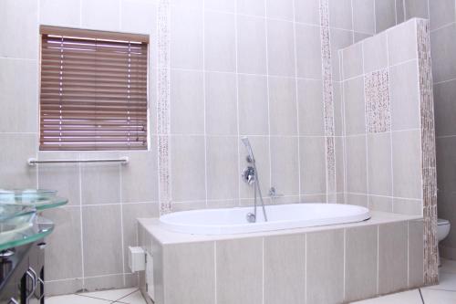 a bathroom with a bath tub with a sink at Ikaze Guest House in Boksburg