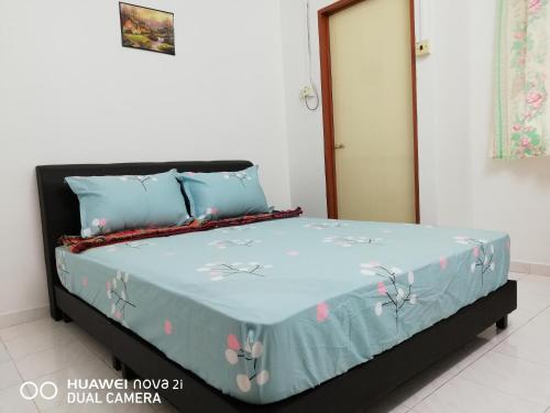 a bed with a blue comforter with flowers on it at Taiping Guest House in Taiping