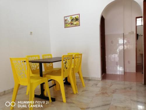 una sala da pranzo con sedie gialle e tavolo di Taiping Guest House a Taiping