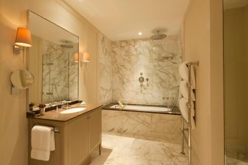 a bathroom with a tub and a sink and a shower at Coworth Park - Dorchester Collection in Ascot