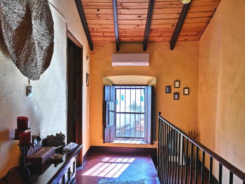 pasillo de una casa con escalera y ventana en Casa centenaria con encanto en Zufre