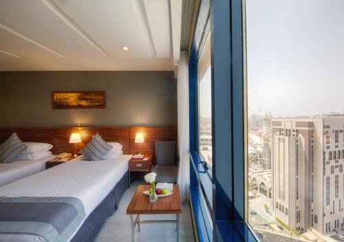 Habitación de hotel con 2 camas y ventana grande. en Al Safwah Royale Orchid Hotel en La Meca