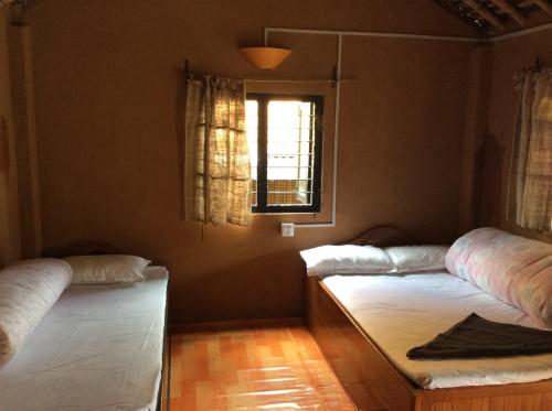 two beds in a room with a window at My beautiful cottage in pokhara in Pokhara