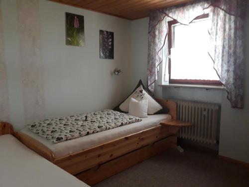 1 dormitorio con cama de madera y ventana en Ferienhof Weydringer, en Haundorf