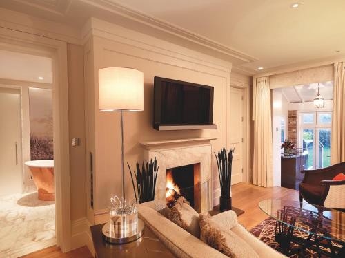a living room with a fireplace and a tv at Coworth Park - Dorchester Collection in Ascot