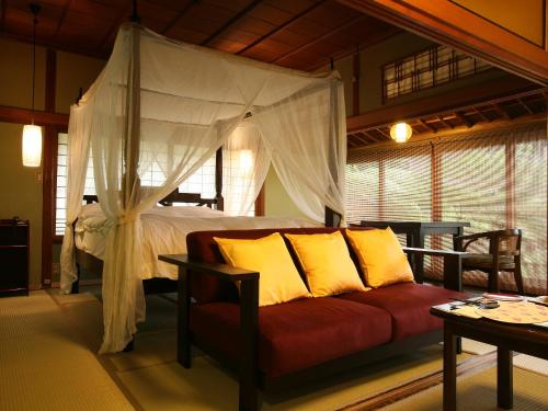 a bedroom with a bed with a red couch and yellow pillows at Kotohira Kadan in Kotohira