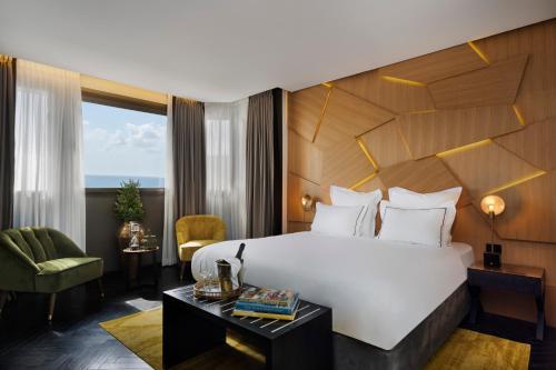 um quarto de hotel com uma cama grande e uma cadeira em Brown Lighthouse Tel Aviv, a member of Brown Hotels em Tel Aviv