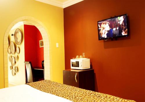 a bedroom with a bed and a tv on the wall at Rekky Signature Guesthouse in Johannesburg