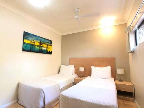a room with two beds and a tv on the wall at City Plaza Apartments in Cairns