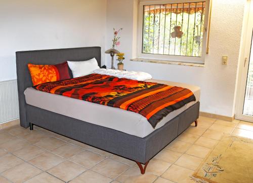 ベンスハイムにあるGästehaus Schäferのベッドルームにオレンジと黒の掛け布団が備わるベッド1台