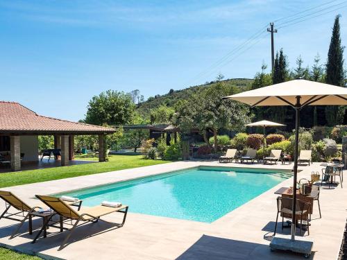 a swimming pool with chairs and an umbrella at Belvilla by OYO Viagrande in Trecastagni