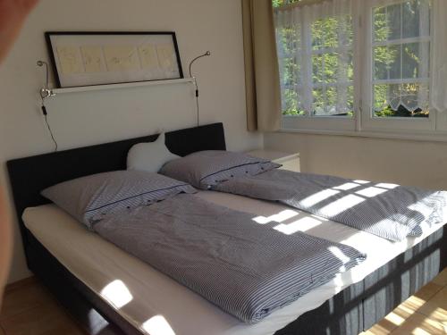 a bed in a bedroom with two windows at Bungalow Beachhouse in Boltenhagen
