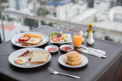 a table with plates of breakfast food on it at Baiyoke Suite Hotel in Bangkok