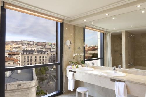 baño con 2 lavabos y ventana grande en Hotel Bahía, en Santander