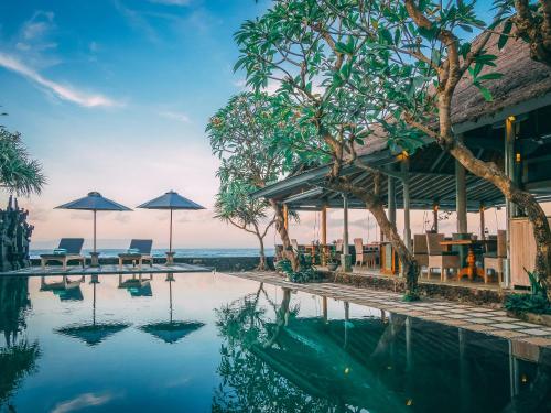 ein Resort mit einem Pool, Tischen und Sonnenschirmen in der Unterkunft Alam Candi Dive Resort in Candidasa