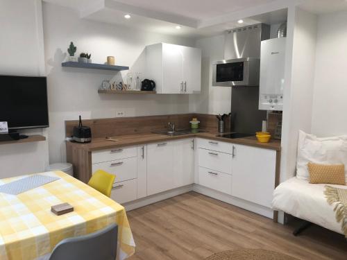 uma cozinha com armários brancos, uma mesa e um sofá em Beau Studio à la Plage em Anglet