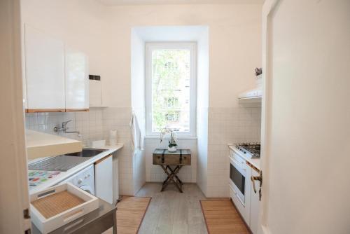 eine weiße Küche mit einem Waschbecken und einem Fenster in der Unterkunft Rome Sweet Home near Metro Flaminio in Rom