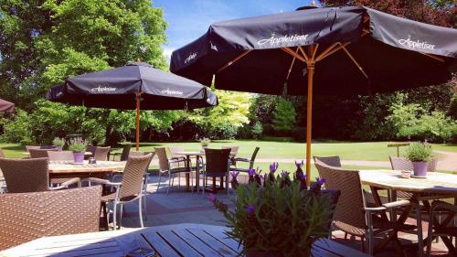 un patio al aire libre con mesas, sillas y sombrillas en Gîtes du Golf, en Sart-Dames-Avelines