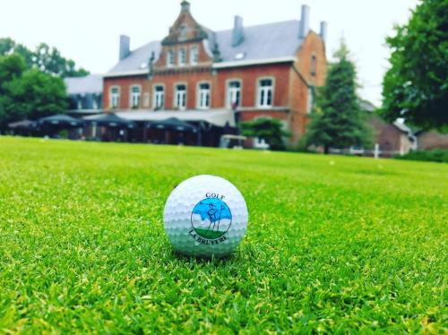 una pelota de golf sentada en el césped frente a una casa en Gîtes du Golf, en Sart-Dames-Avelines