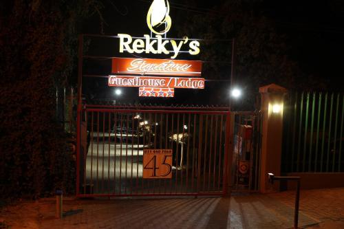 a gate with a sign for a restaurant at night at Rekky Signature Guesthouse in Johannesburg