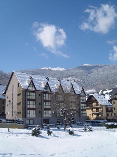 a building in the snow with snow covered roofs at Aparthotel La Vall Blanca in Vielha