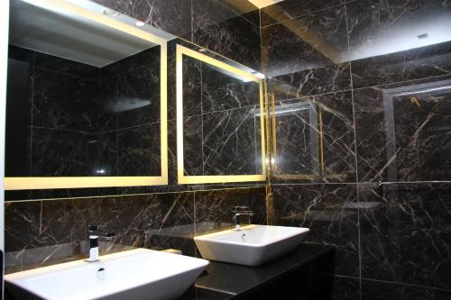 a black tiled bathroom with two sinks and mirrors at Privilege Hotel & Spa in Tirana