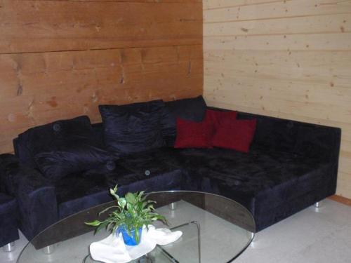a black couch with red pillows and a glass table at Ferienwohnung Brülisauer in Brülisau