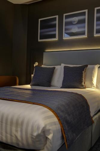 a bedroom with a large bed with blue and white pillows at Best Western Plus Vauxhall Hotel in London