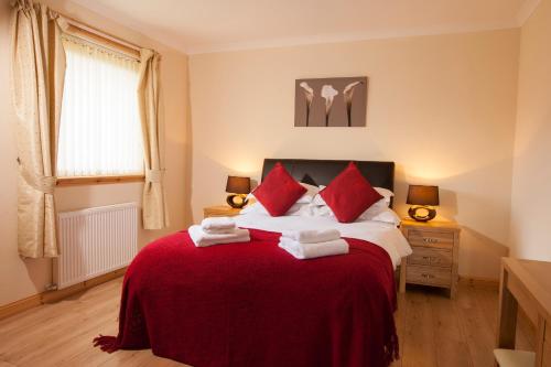 a bedroom with a large bed with a red blanket at Borve House Hotel in Borve